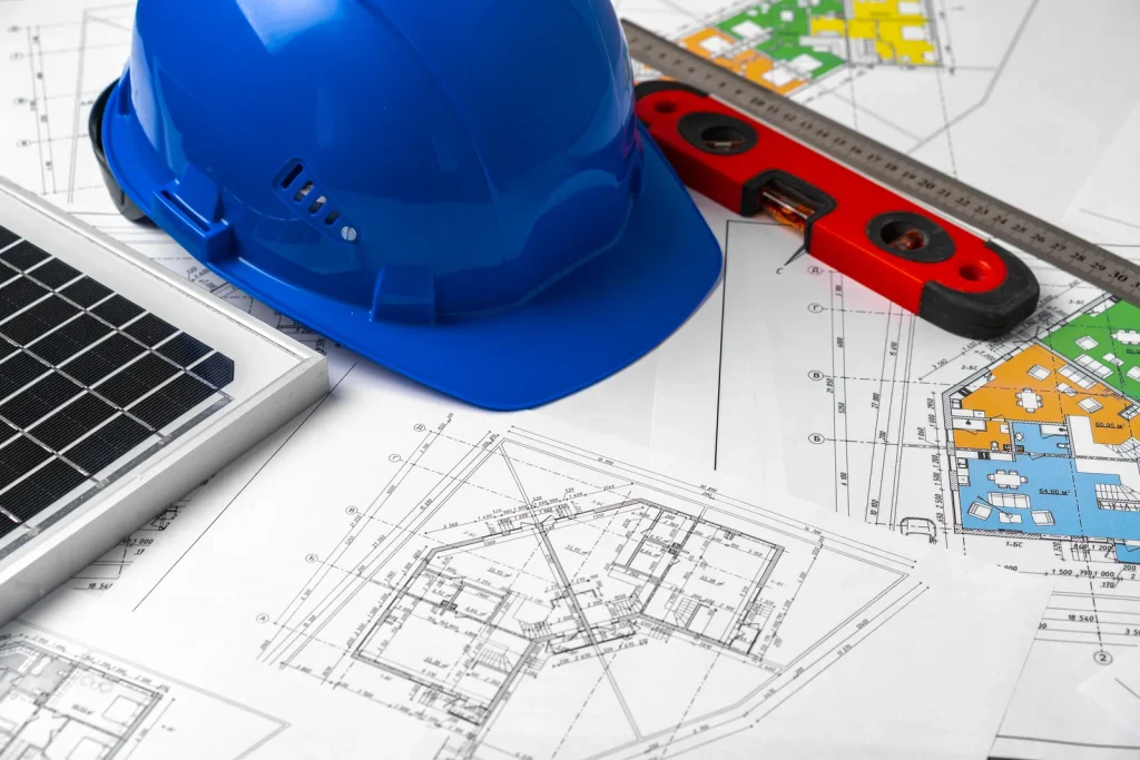 Proje çizimleri üzerinde baret ve güneş paneli – Atre Global mühendislik hizmetleri